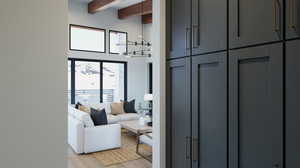 Living room with a high ceiling, beamed ceiling, light hardwood / wood-style floors, and a notable chandelier