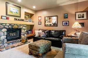 Carpeted living room featuring a stone fireplace