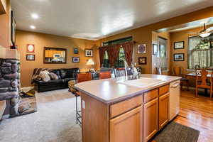 Kitchen with a textured ceiling, an island with sink, dishwasher, sink, and ceiling fan