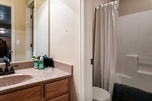 Full bathroom with shower / bathtub combination with curtain, vanity, and toilet