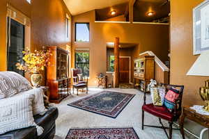 Carpeted living room featuring beamed ceiling and high vaulted ceiling