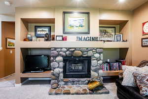 Living room featuring built in shelves, carpet, a textured ceiling, and a fireplace