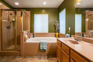 Bathroom featuring tile floors, vanity with extensive cabinet space, and plus walk in shower