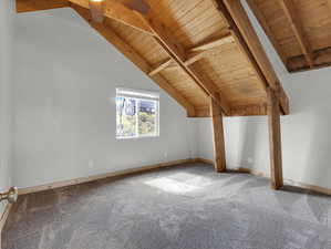 Bonus room featuring carpet flooring, wood ceiling, and lofted ceiling with beams