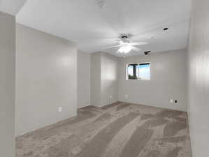 Empty room with a textured ceiling, carpet flooring, and ceiling fan