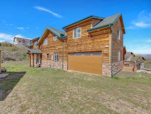 Back of house featuring a garage and a yard