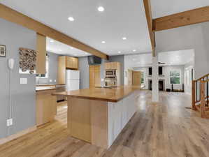 Kitchen featuring wooden counters, a multi sided fireplace, light wood-type flooring, and stainless steel appliances