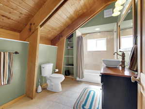 Full bathroom with oversized vanity, lofted ceiling with beams, shower / bath combo, tile floors, and toilet