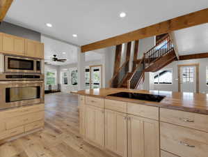 Kitchen with appliances with stainless steel finishes, butcher block countertops, light wood-type flooring, and light brown cabinets