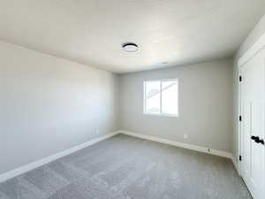 Bedroom with light carpet, visible vents, baseboards, and a textured ceiling