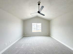 Primary bedroom featuring light carpet, baseboards, lofted ceiling, ceiling fan, and a textured ceiling