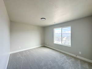 Bedroom with a textured ceiling, carpet flooring, visible vents, and baseboards