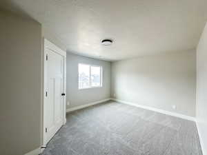 Bedroom with a textured ceiling, carpet floors, and baseboards