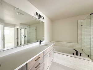 Primary bath featuring a garden tub, a stall shower, vanity, a textured ceiling, and tile patterned flooring