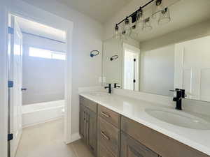 Full bathroom with toilet, double vanity, a sink, and tile patterned floors
