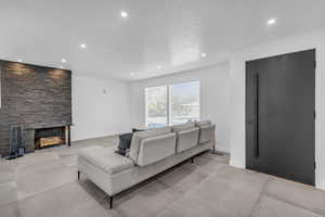 Living room featuring a stone fireplace and tile flooring