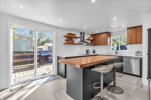 Kitchen with tasteful backsplash, stainless steel dishwasher, wooden counters, light tile floors, and wall chimney range hood