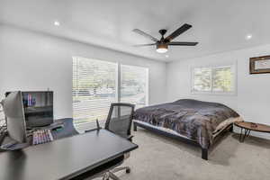 Carpeted bedroom with multiple windows and ceiling fan