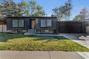 View of front of home with a garage and a front lawn