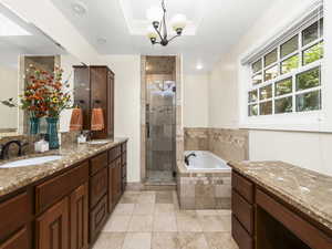 Master bathroom featuring tile floors, a raised ceiling, separate shower and tub, and double sink vanity