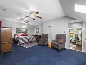 Carpeted bedroom with lofted ceiling with skylight and ceiling fan