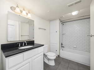 Full bathroom with tile flooring, tiled shower / bath combo, vanity, and toilet