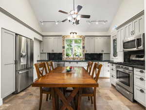 Kitchen with gray cabinetry, appliances with stainless steel finishes, tasteful backsplash, track lighting, and ceiling fan