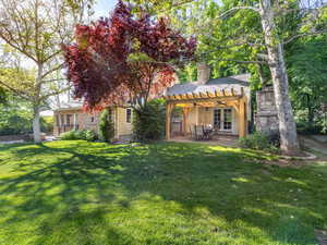 View backyard terrace with entrance from living room, and master bedroom, a pergola, ceiling fans, and a brick fireplace.