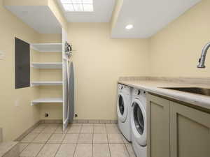 Main level laundry room with sink and storage, light tile flooring, and washing machine and clothes dryer