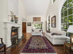 Living room featuring a high end fireplace, high vaulted ceiling, and dark hardwood / wood-style flooring