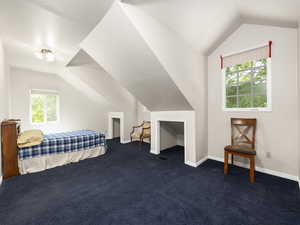 Large oversized bedroom with dormer windows, dark colored carpet and lofted ceiling