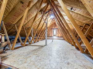 View of unfinished attic accessed from a bedroom.