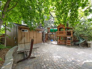 View of patio with a playground and large storage shed (with power)