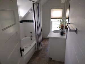 Bathroom with tile walls, tile floors, vanity, and shower / bath combo with shower curtain