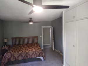 Bedroom featuring a textured ceiling, carpet flooring, a closet, and ceiling fan