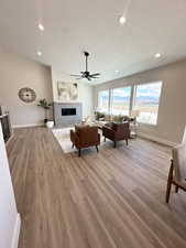 Living room with ceiling fan, a textured ceiling, and light hardwood / wood-style flooring