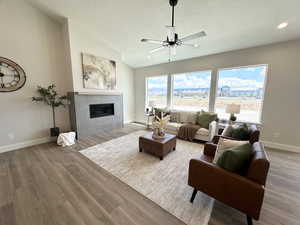 Living room featuring ceiling fan, lofted ceiling, a textured ceiling, and light wood-type flooring
