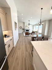 Kitchen with light hardwood / wood-style floors, tasteful backsplash, light brown cabinets, a tiled fireplace, and pendant lighting