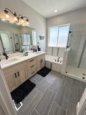 Bathroom with a textured ceiling, independent shower and bath, dual bowl vanity, and tile patterned floors