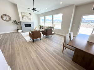 Living room featuring ceiling fan, a textured ceiling, light hardwood / wood-style flooring, and lofted ceiling