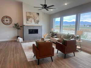 Living room with a mountain view, a textured ceiling, ceiling fan, a tiled fireplace, and hardwood / wood-style flooring