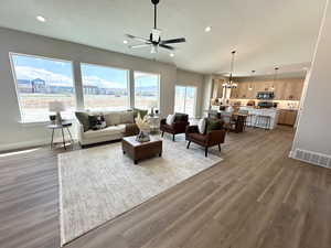 Living room with ceiling fan with notable chandelier, hardwood / wood-style floors, and a textured ceiling