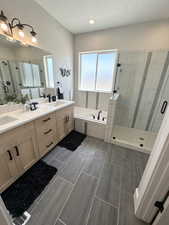 Bathroom with tile patterned flooring, separate shower and tub, double vanity, and a textured ceiling