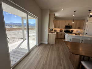 Kitchen with a mountain view, tasteful backsplash, appliances with stainless steel finishes, light hardwood / wood-style floors, and decorative light fixtures