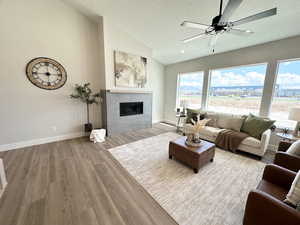 Living room with ceiling fan, vaulted ceiling, a textured ceiling, and wood-type flooring