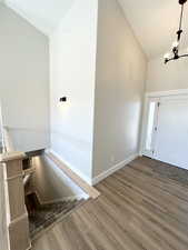 Entryway featuring high vaulted ceiling, a notable chandelier, and hardwood / wood-style floors