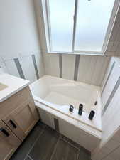 Bathroom featuring tile flooring, plenty of natural light, and tiled bath