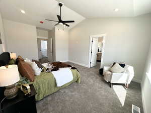 Carpeted bedroom with ceiling fan, vaulted ceiling, and ensuite bathroom
