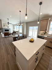 Kitchen with dark hardwood / wood-style floors, a tile fireplace, tasteful backsplash, light brown cabinetry, and a center island