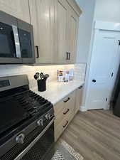Kitchen featuring appliances with stainless steel finishes, light brown cabinets, decorative backsplash, and light wood-type flooring